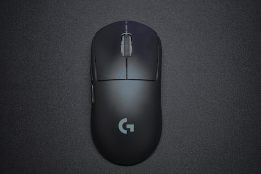 A sleek black gaming mouse with a matte finish and a central scroll wheel, featuring a logo near the bottom, positioned against a dark background.