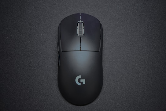 A sleek black gaming mouse with a matte finish and a central scroll wheel, featuring a logo near the bottom, positioned against a dark background.