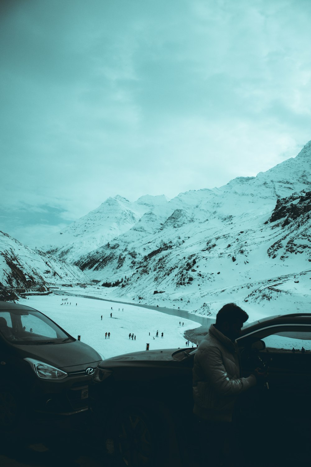a person sitting in a car in front of a snowy mountain