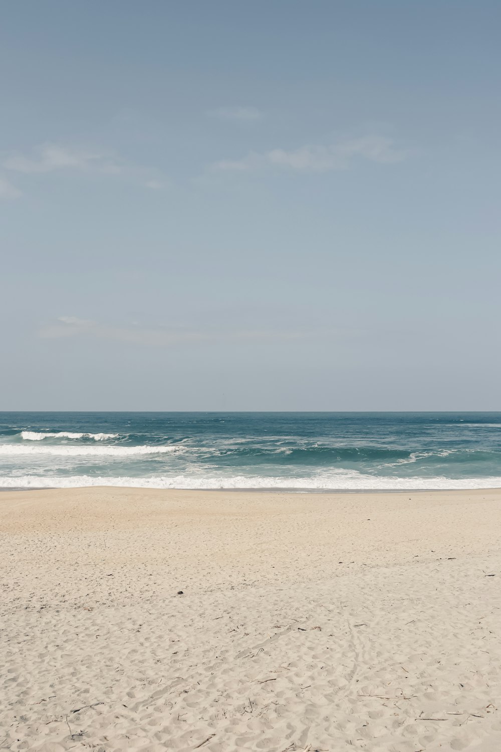 a person walking on a beach carrying a surfboard