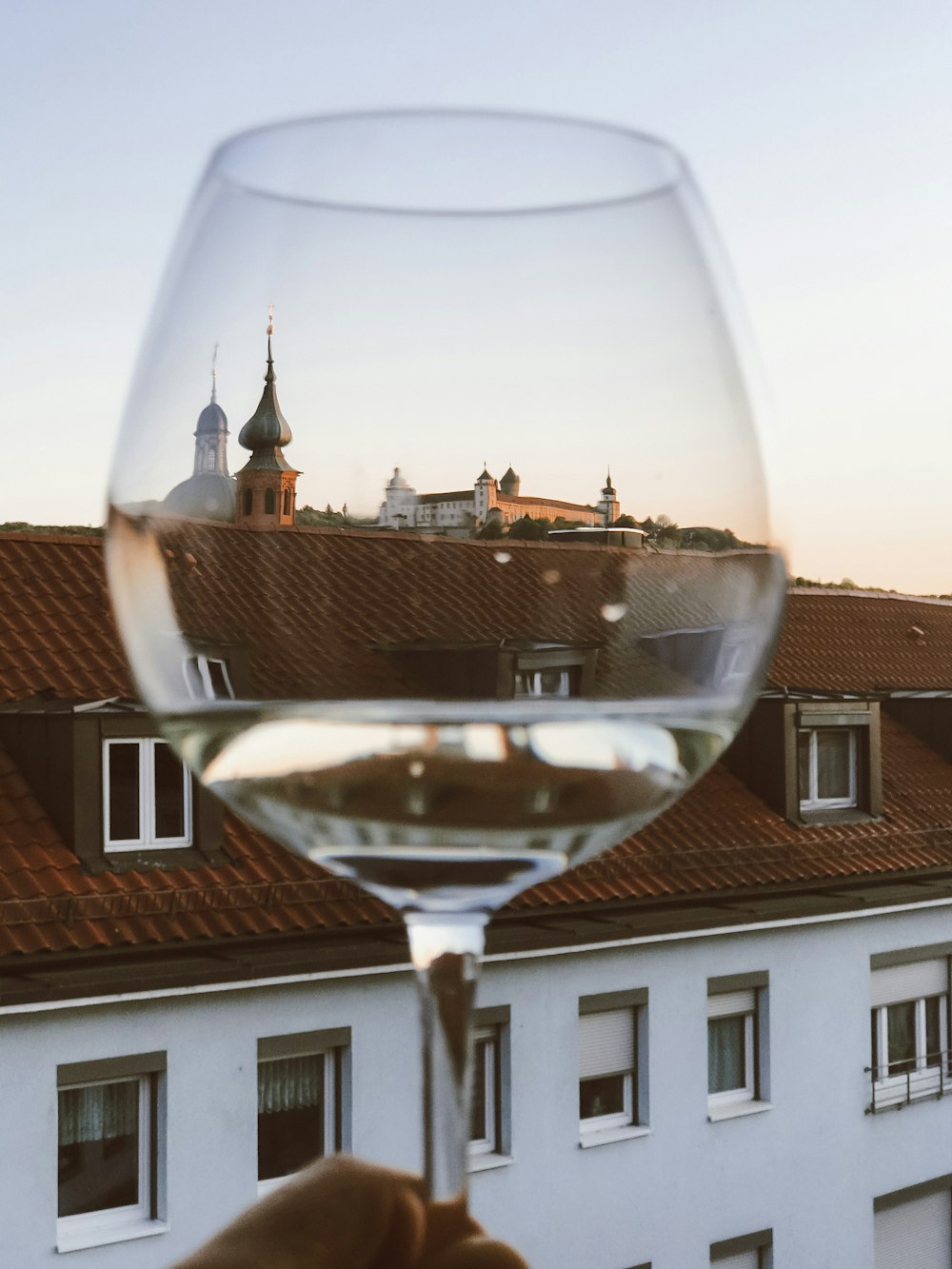 a hand holding a wine glass in front of a building