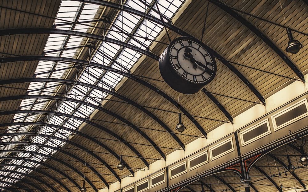 a clock hanging from the ceiling of a train station