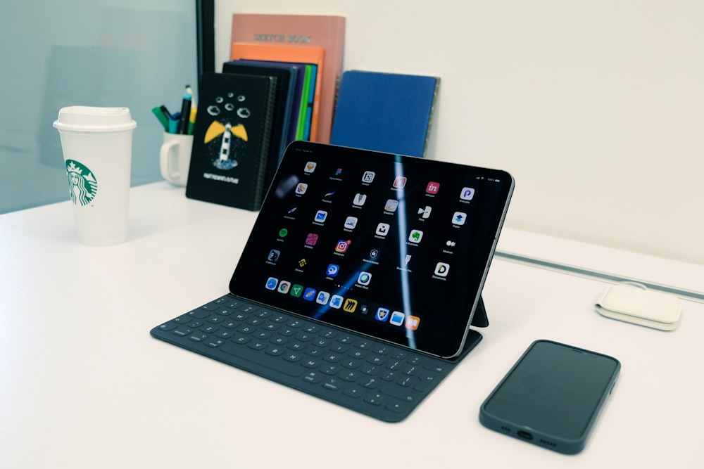 a tablet sitting on top of a desk next to a cup of coffee