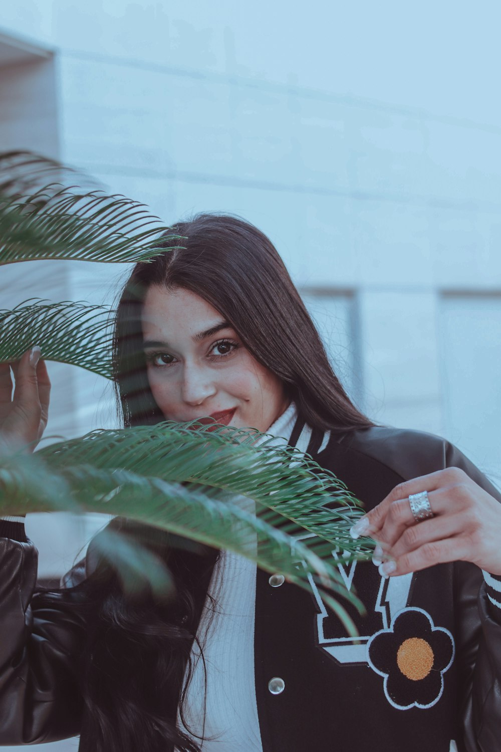 a woman in a black jacket is holding a plant