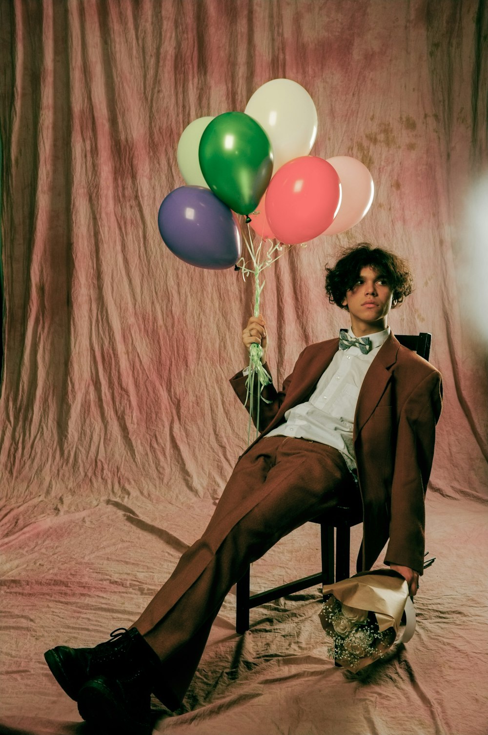 a man sitting in a chair holding a bunch of balloons