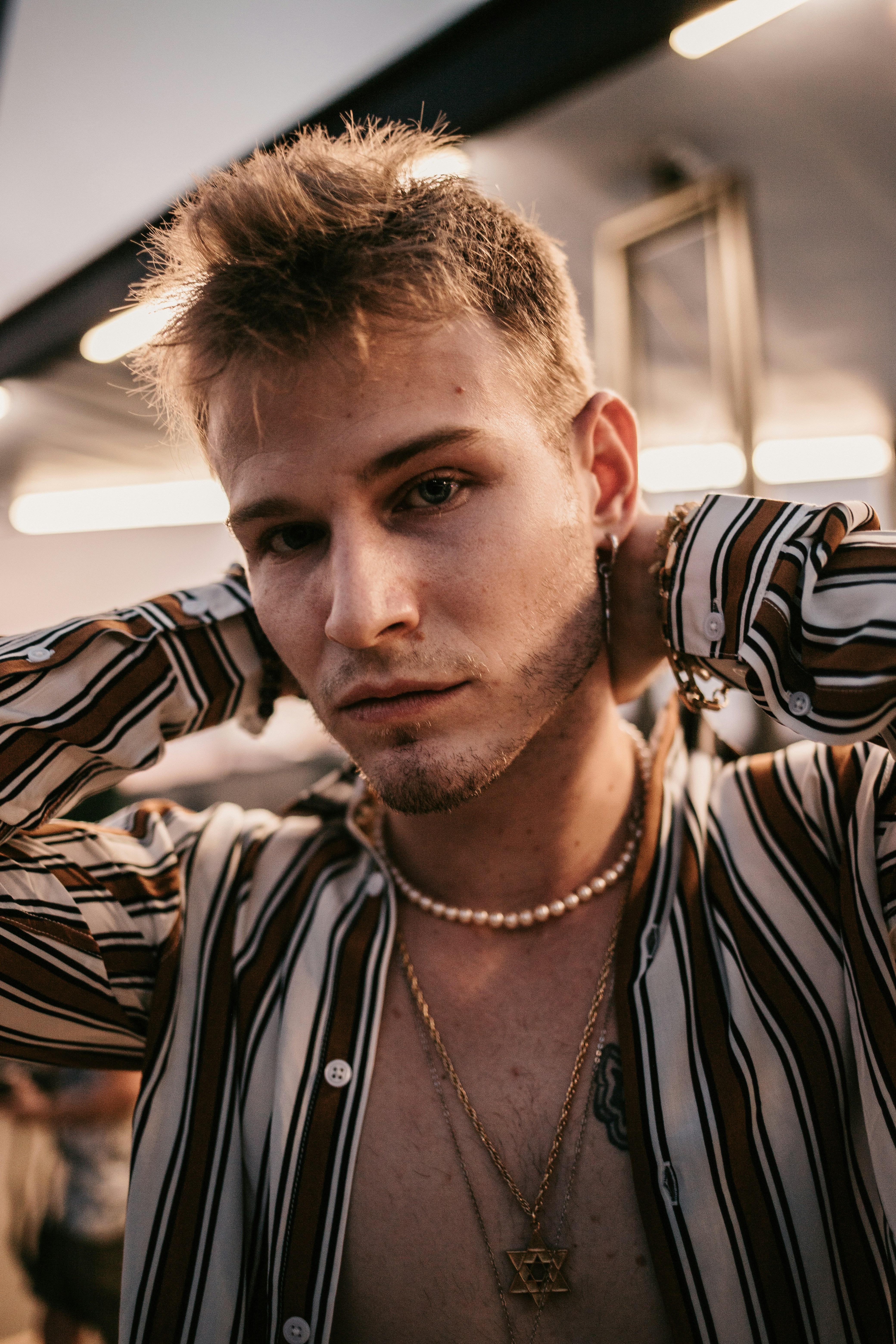 un uomo che indossa una collana e una camicia a righe
