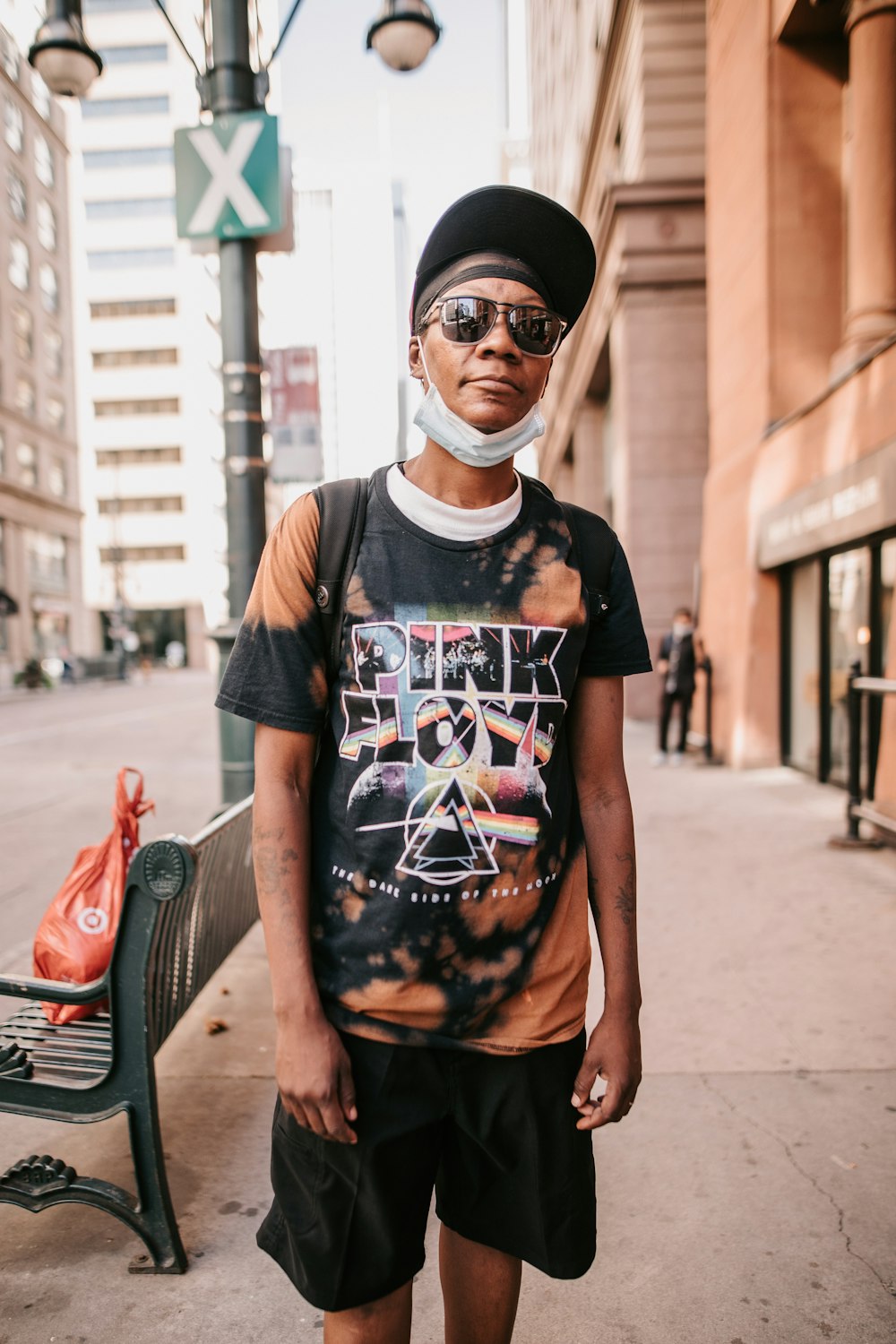 a man standing on a sidewalk wearing a tie dye shirt