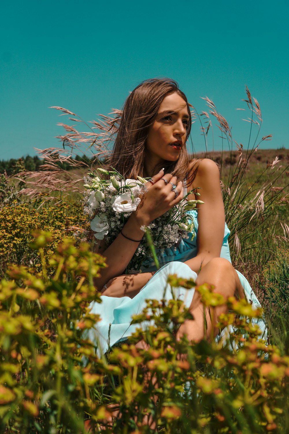 a woman in a blue dress sitting in a field