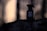 A bottle of Tom Ford Oud Wood eau de parfum sits on a rugged surface, with a soft, blurred background that suggests an outdoor setting. The image captures a moody, atmospheric lighting with shadows and a warm tone.