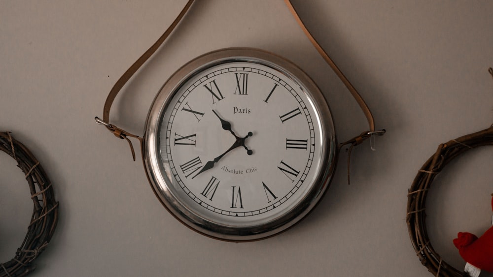 a clock hanging on a wall next to a wreath