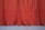 An artistic shot of a man practicing lines with a red velvet curtain backdrop, evoking old Hollywood charm.