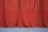A long red curtain extends from ceiling to floor, creating a rich and dramatic backdrop. The surface of the curtain has subtle folds and drapes that give it texture. The floor beneath is a smooth blue with two painted lines, one red and one yellow, suggesting a sports or auditorium setting.