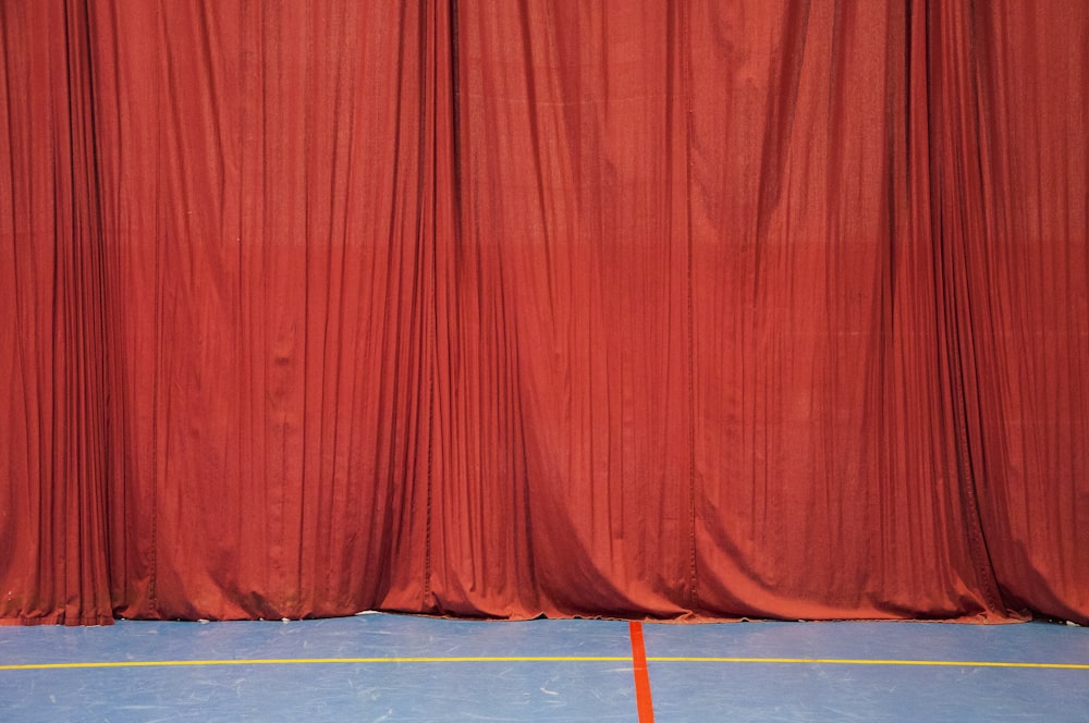 a basketball court with a red curtain and a blue floor