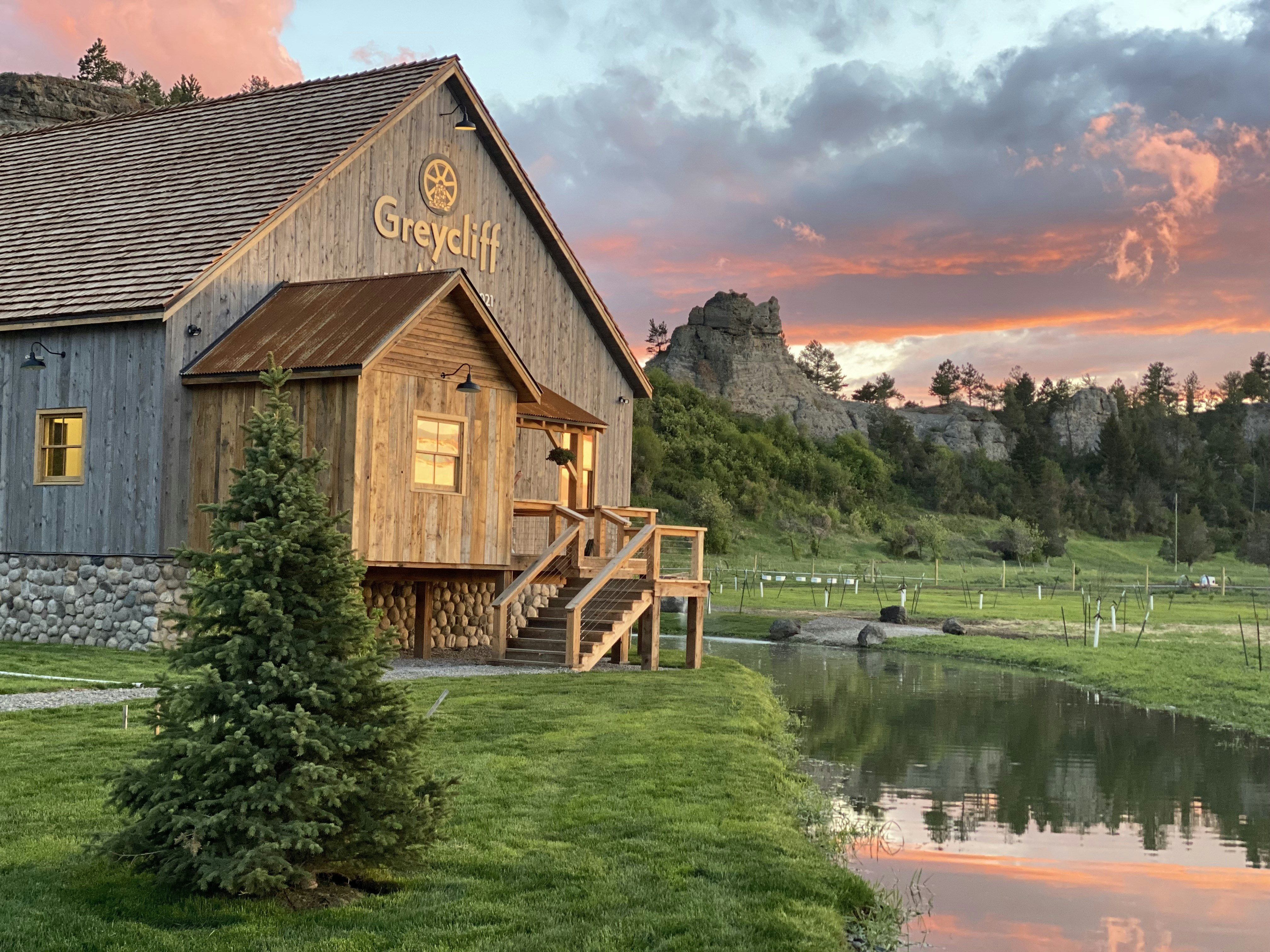 a wooden building sitting on top of a lush green field