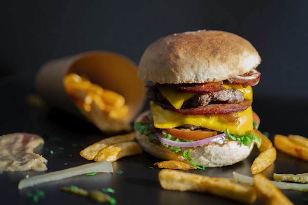 A hamburger with bacon, cheese, lettuce and tomato