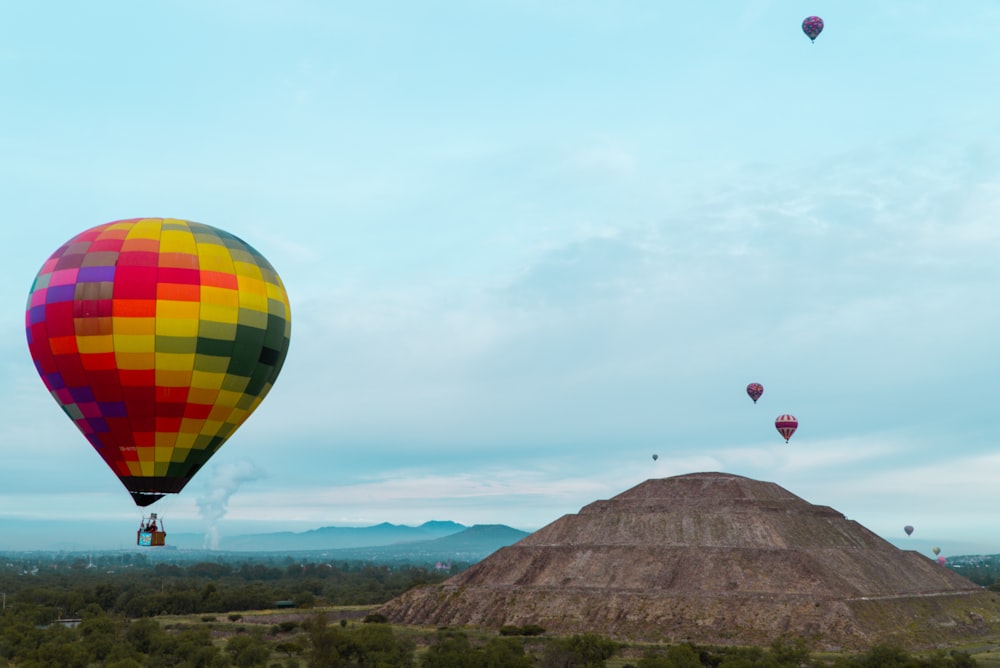 um grupo de balões de ar quente voando sobre uma colina