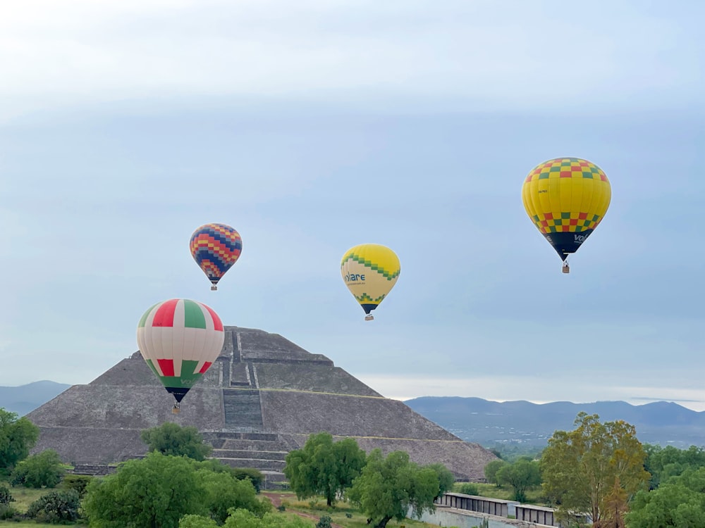 a group of hot air balloons flying over a pyramid