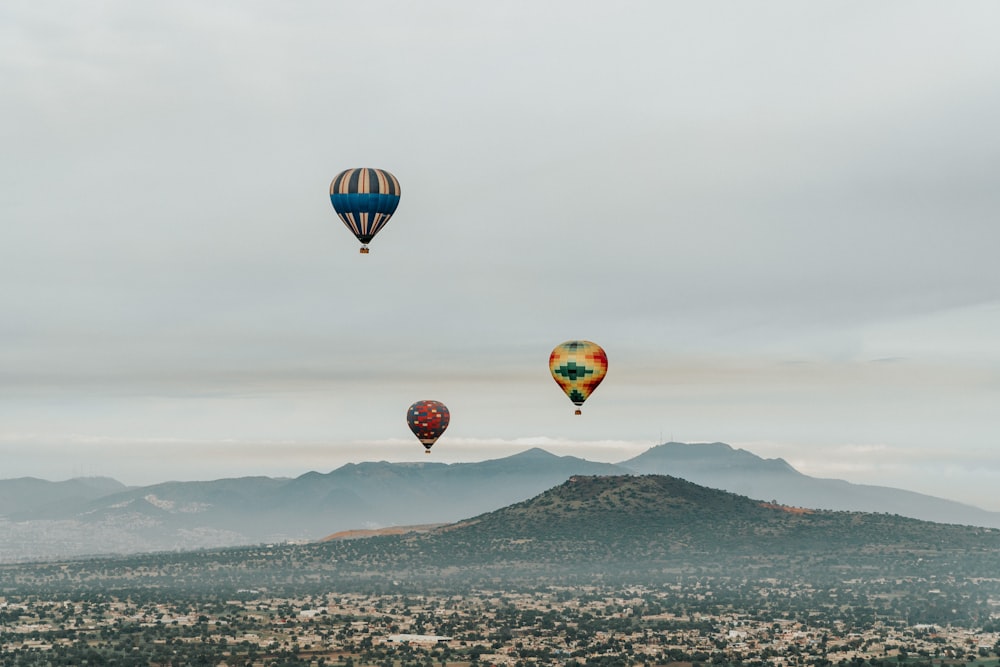 a group of hot air balloons flying over a mountain