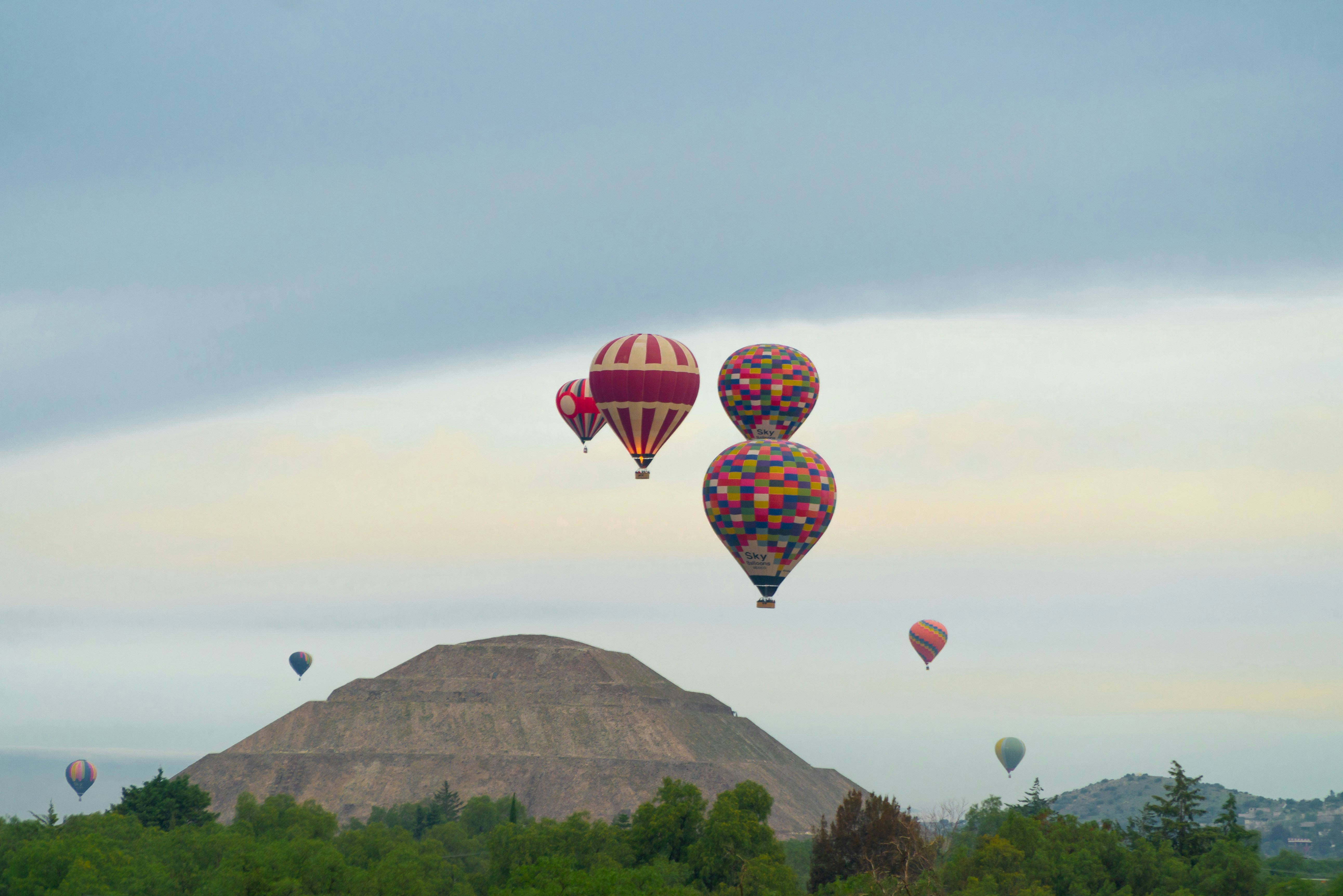 a group of hot air balloons flying over a mountain, 