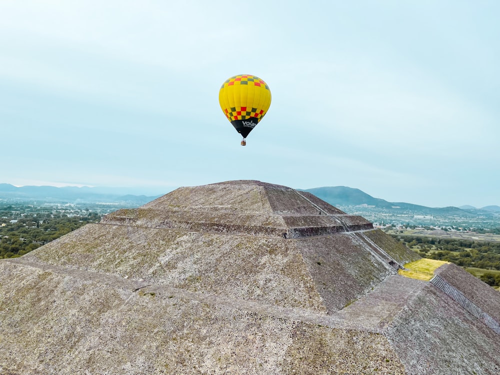 a hot air balloon flying over a pyramid