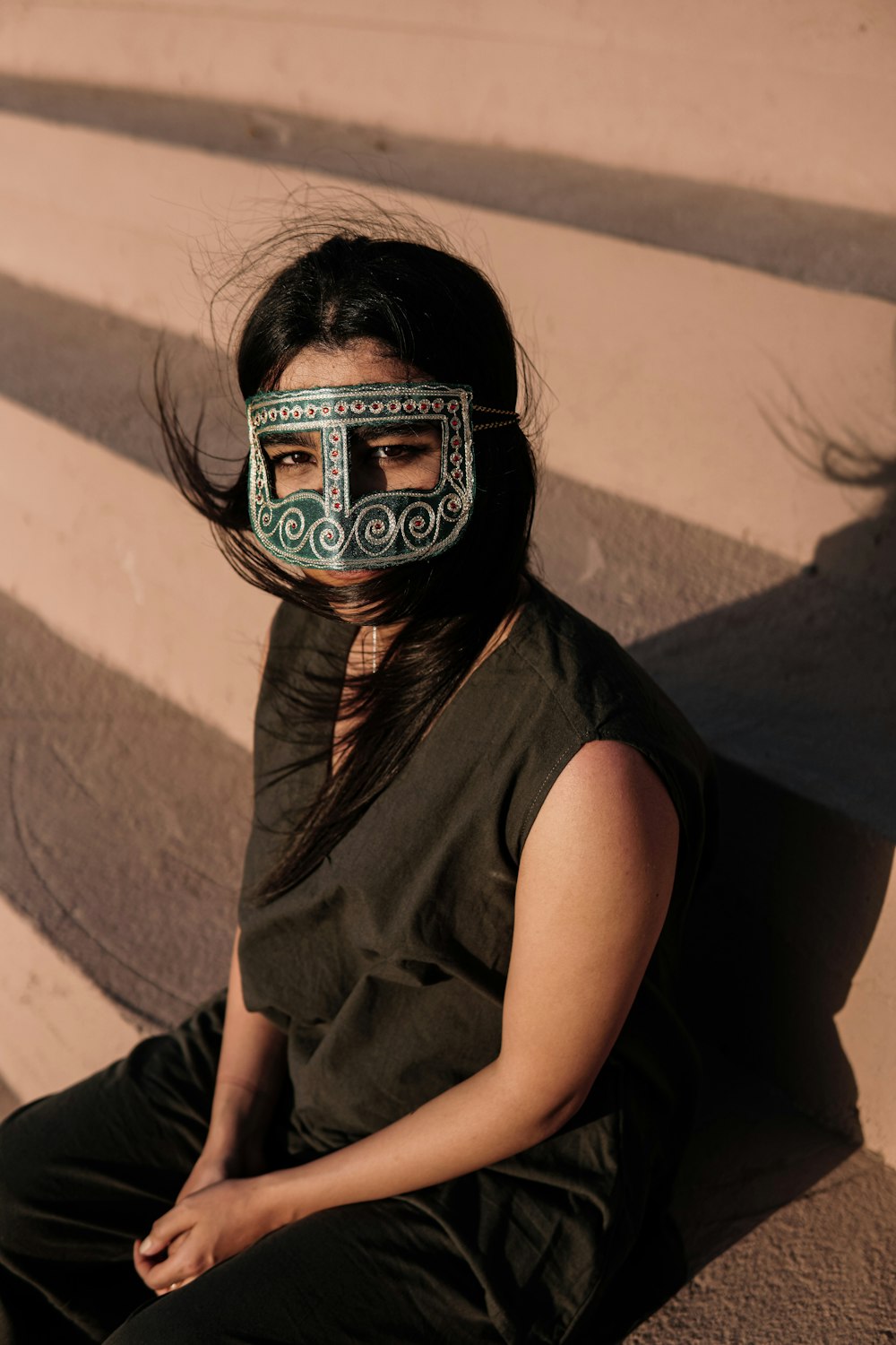 a woman wearing a mask sitting on the ground