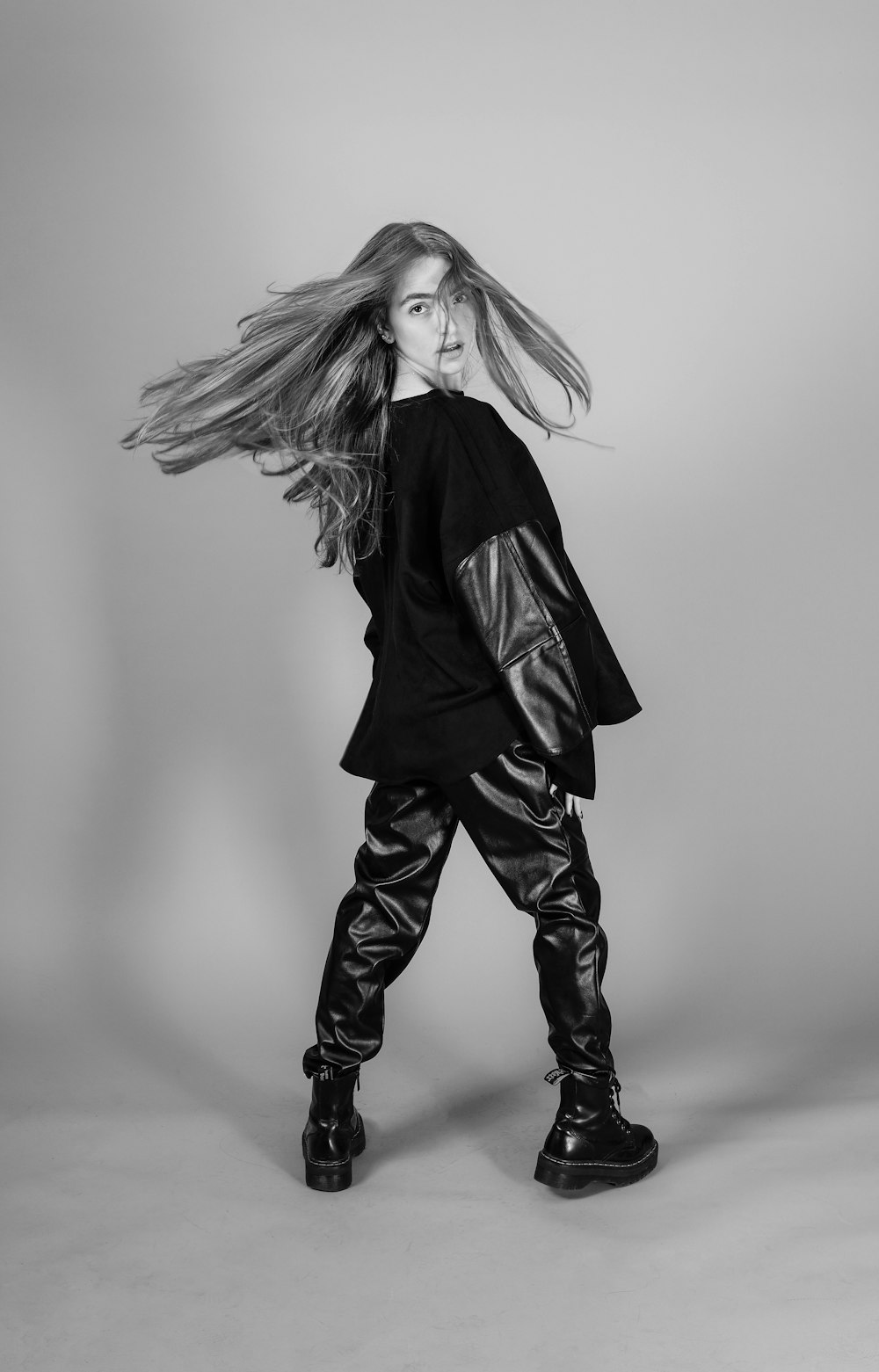 a woman with long hair standing in front of a gray background