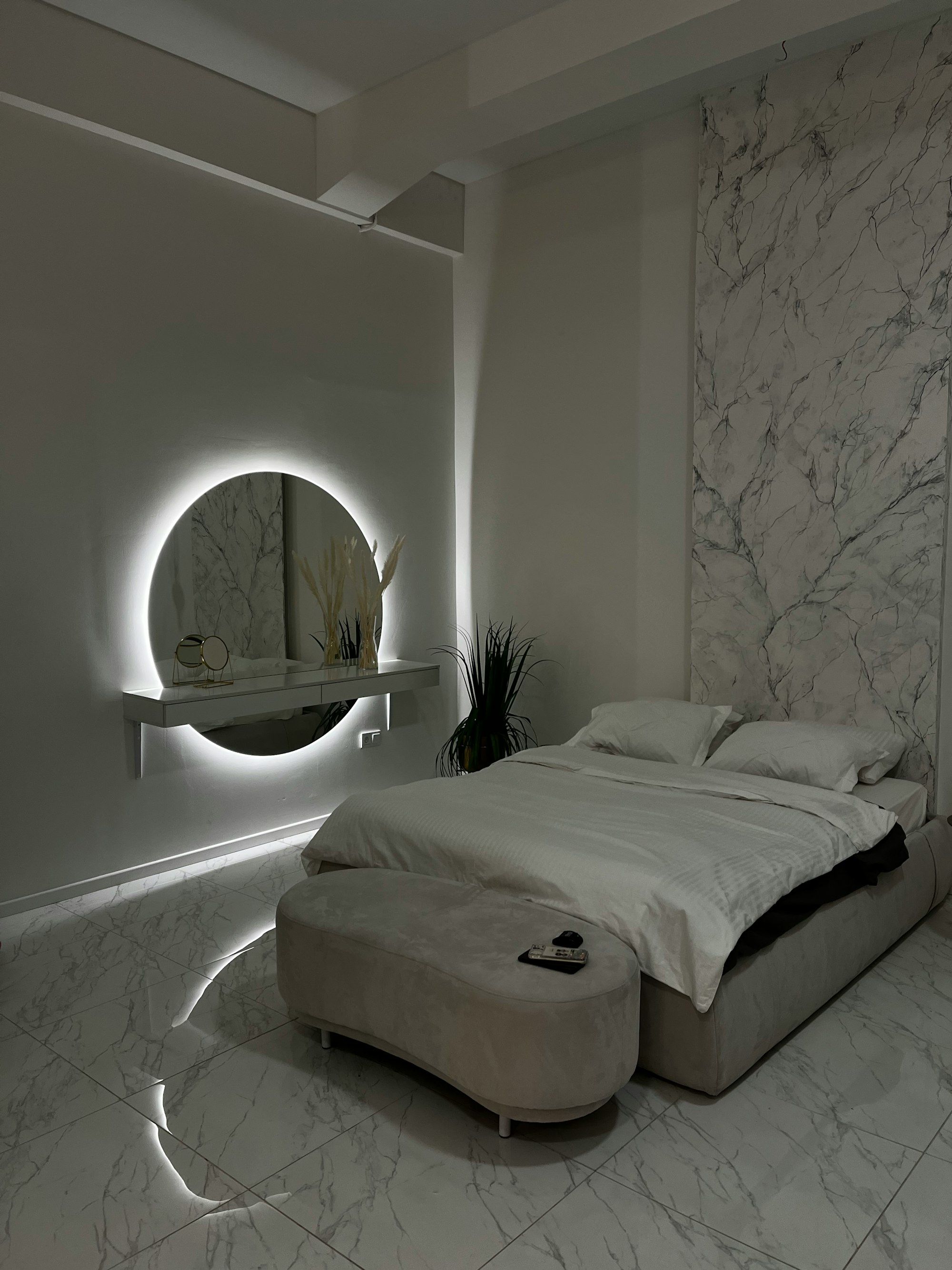 a bedroom with a marble wall and a round mirror