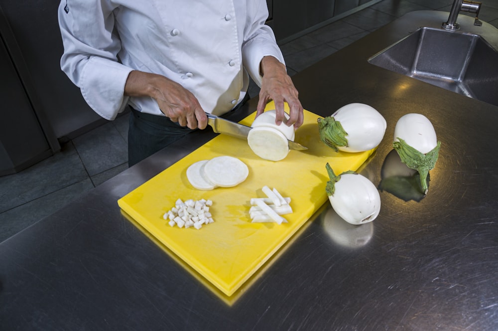 a chef chopping onions on a yellow cutting board