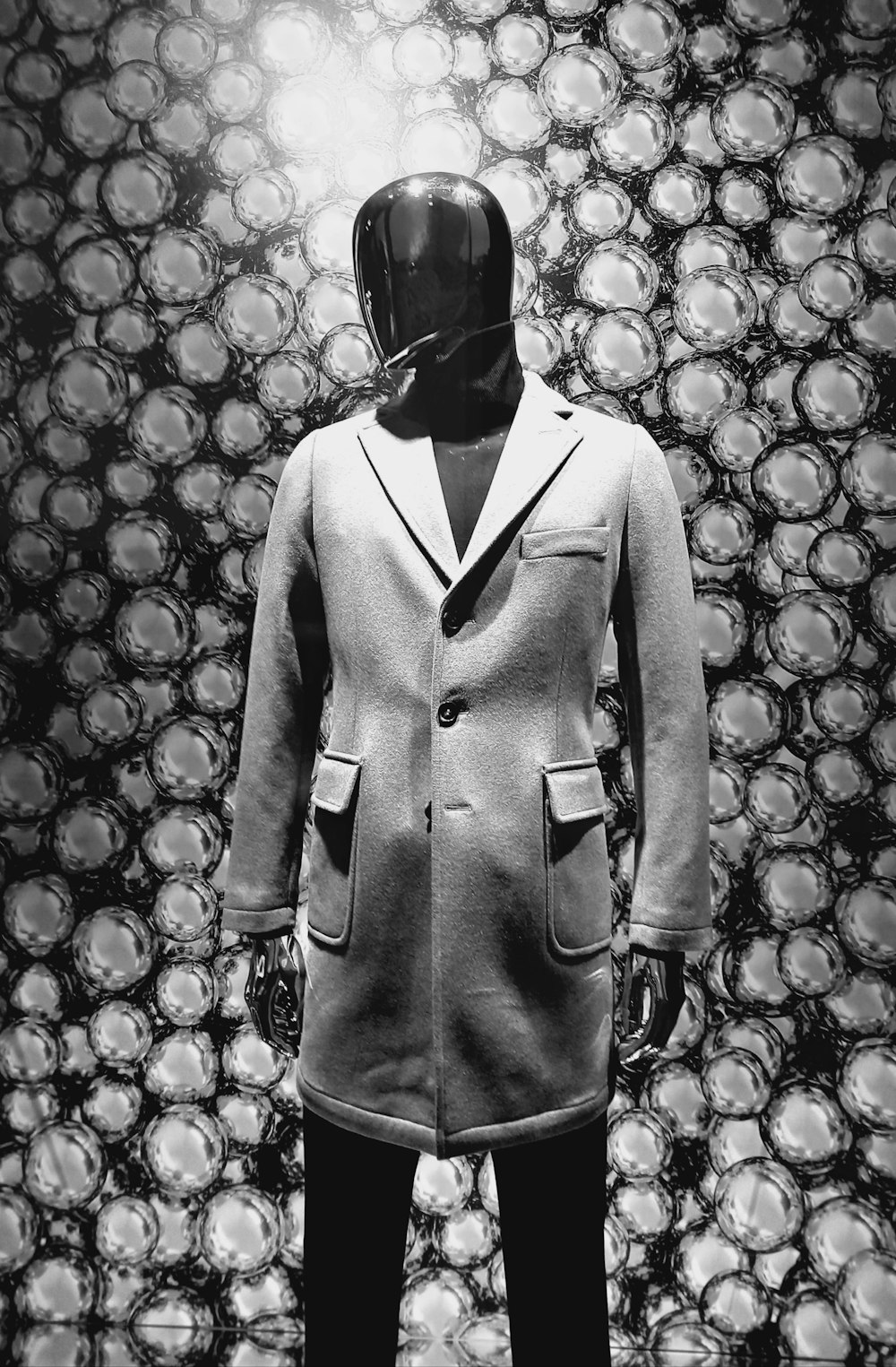 a black and white photo of a mannequin wearing a coat