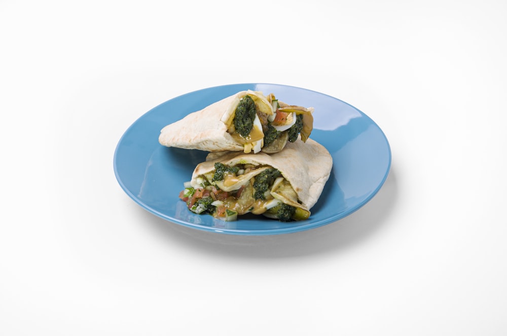 a blue plate topped with two burritos on top of a white table