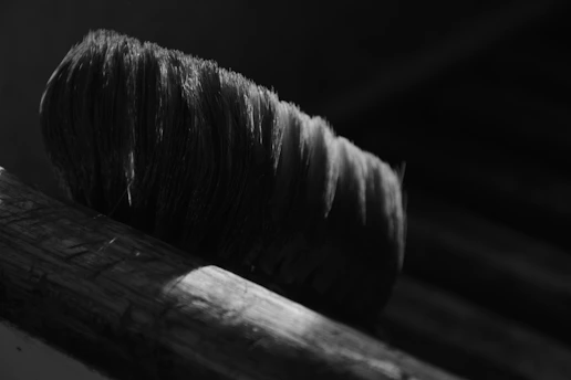 Close-up of a high-quality paintbrush resting on a vibrant orange and deep navy background, highlighting bristle detail.