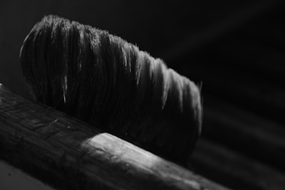 Close-up of a paintbrush loaded with creamy white paint against a black background.