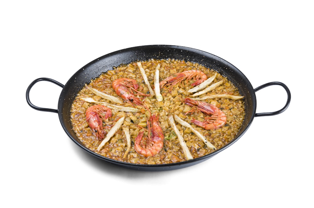a pan filled with rice and shrimp on top of a white table