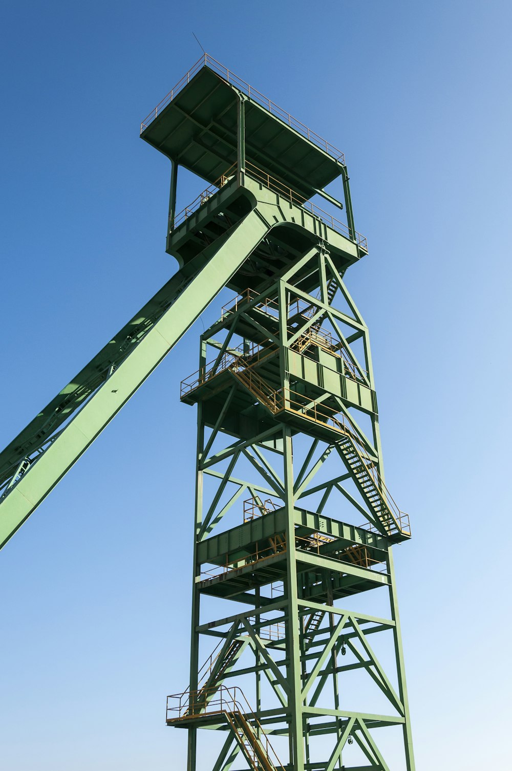 a tall green metal structure with a sky background