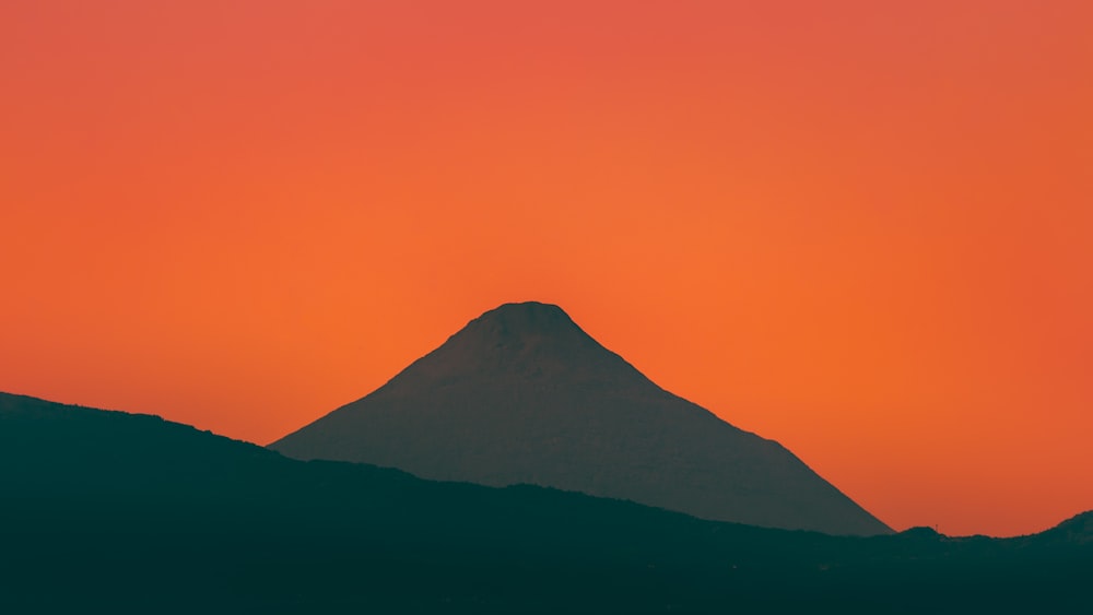 a mountain with a red sky in the background