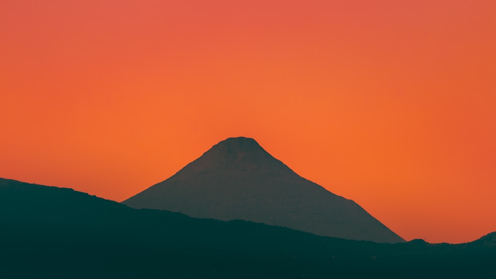 uma montanha com um céu vermelho no fundo