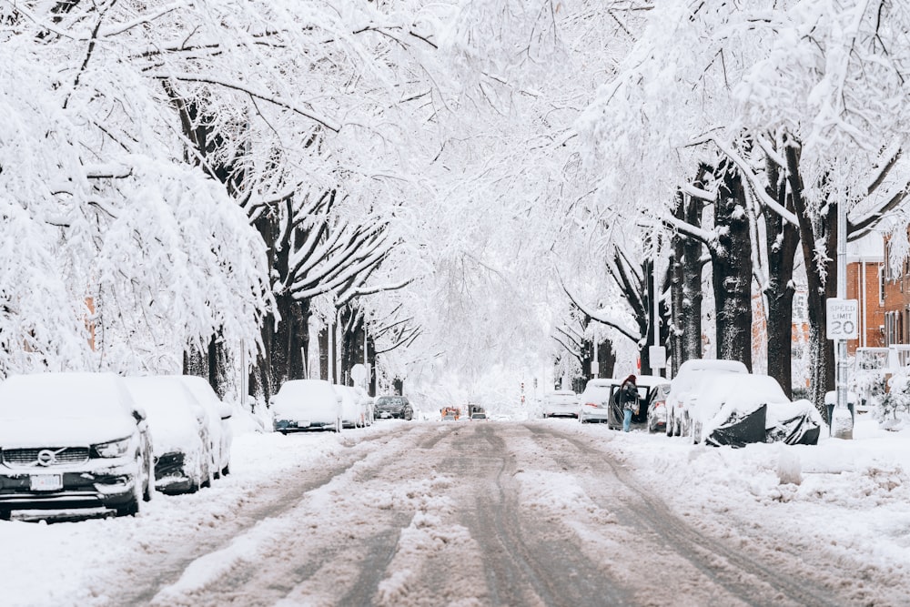 a snowy street with cars parked on the side of it