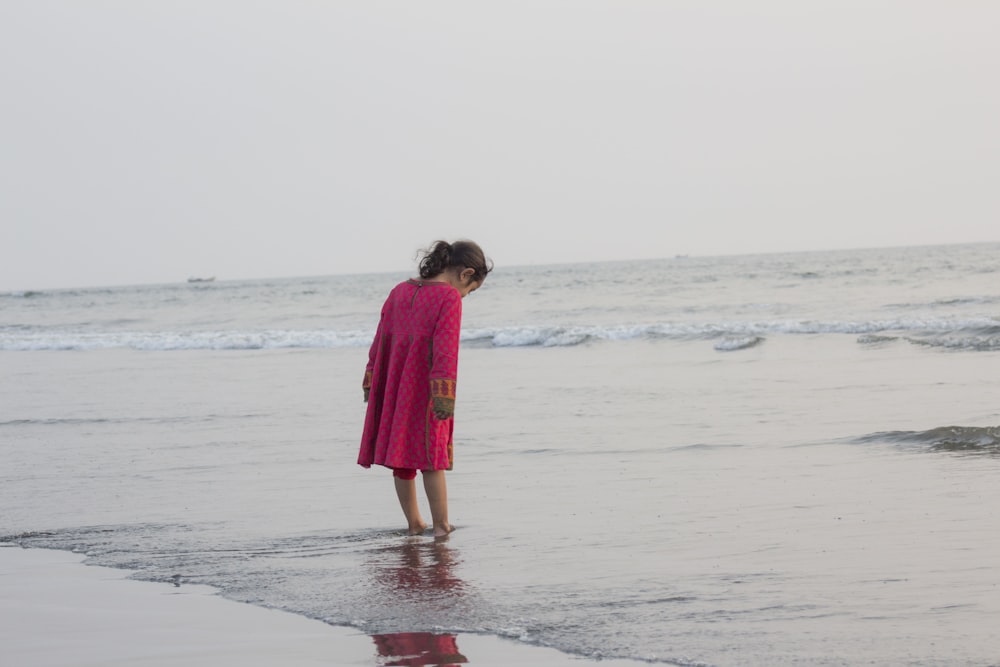 a little girl standing in the water at the beach