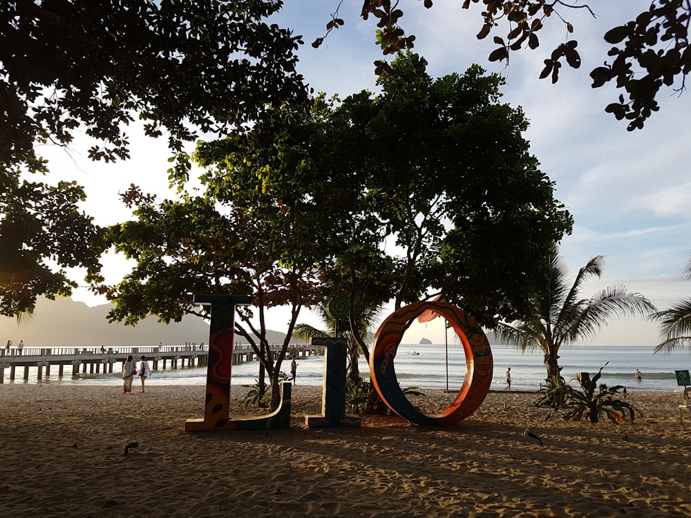 a sign that is on the sand near a tree