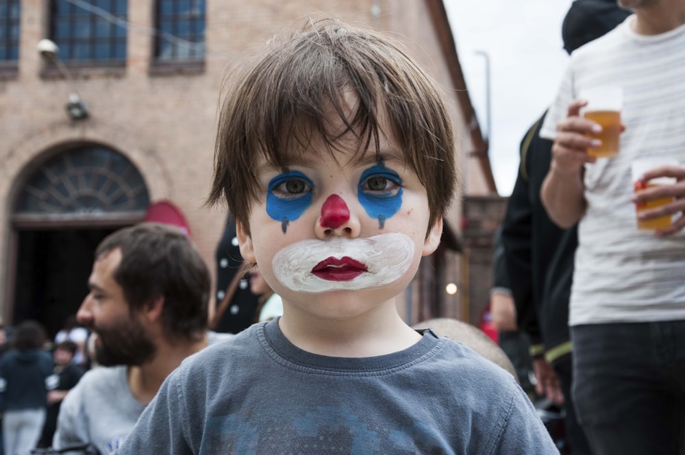 a young boy with a clown nose painted on his face