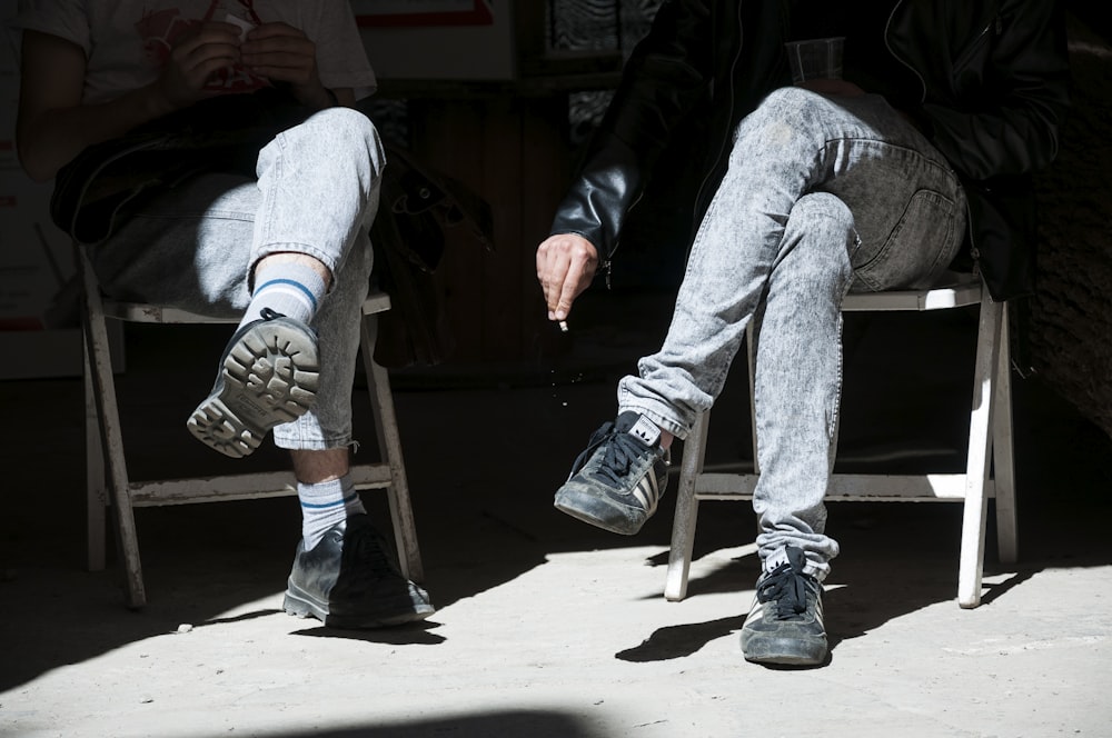 two people sitting in chairs with their legs crossed