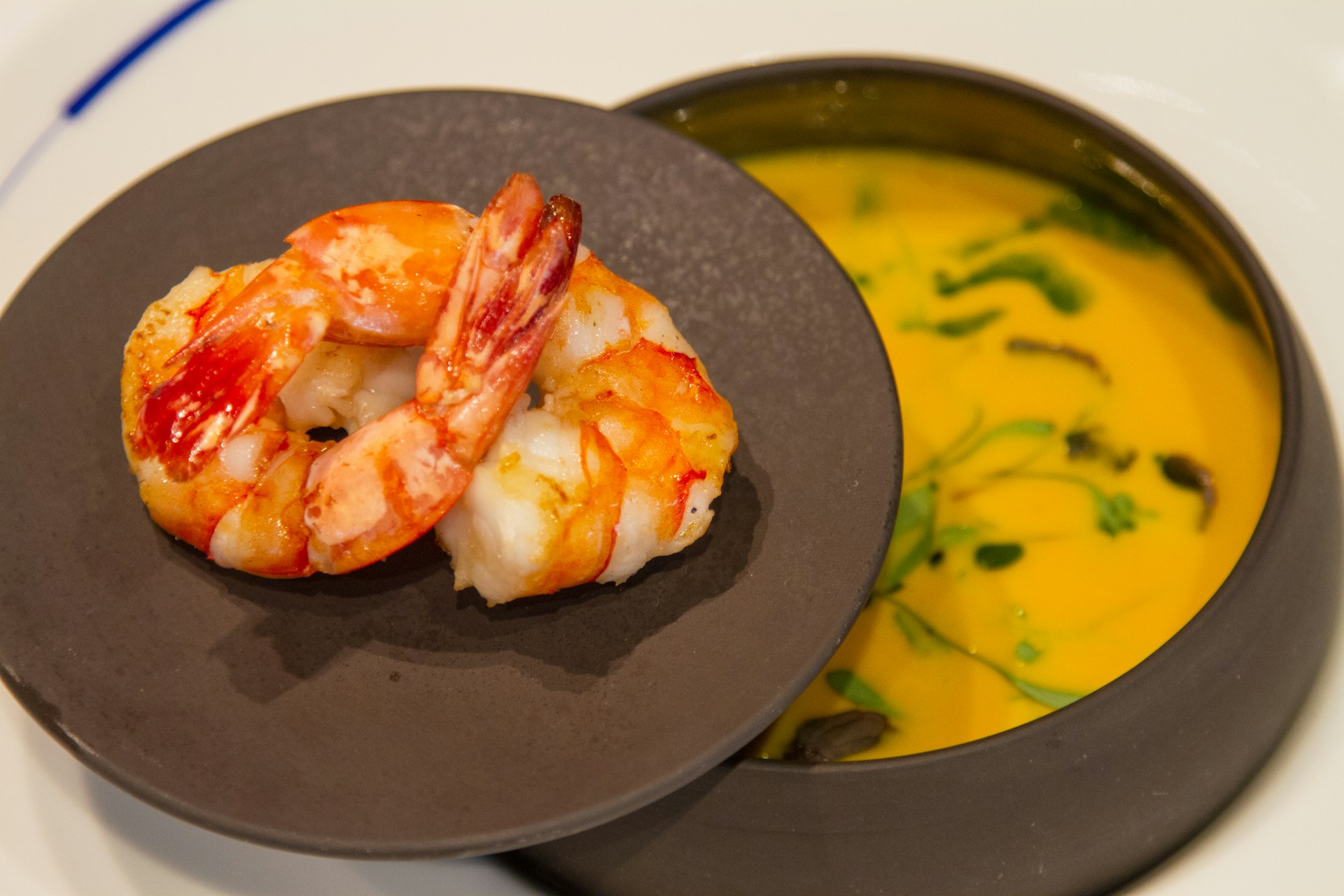 A vibrant plate of southern-style shrimp and grits, topped with a rich, spicy sauce and a sprinkle of green onions.