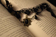 An elegant necklace resting on an open book with a vintage feel.