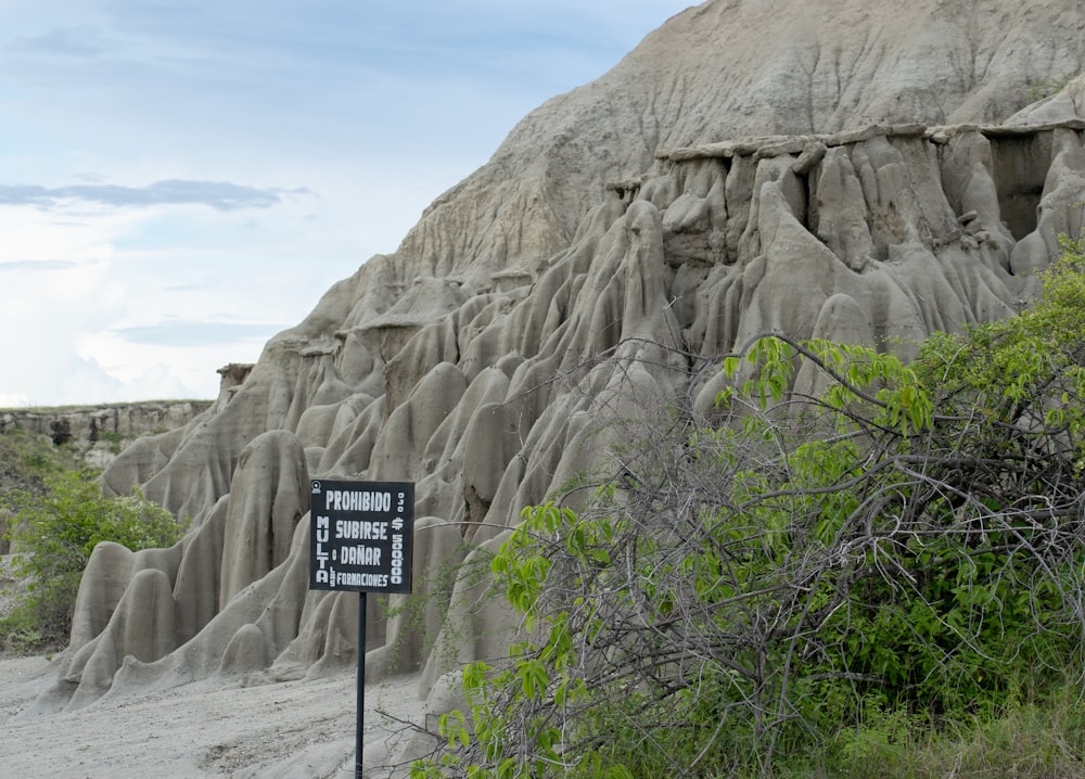 a sign in front of a large rock formation