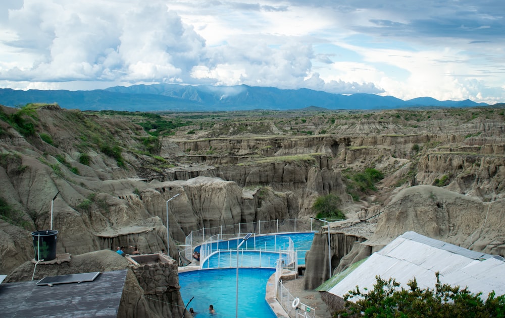 a large swimming pool surrounded by mountains under a cloudy sky