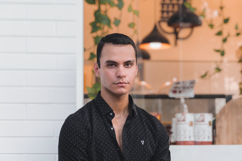 a man standing in front of a white brick wall