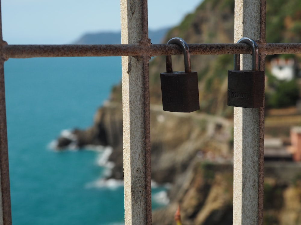 a couple of padlocks on a gate near a body of water