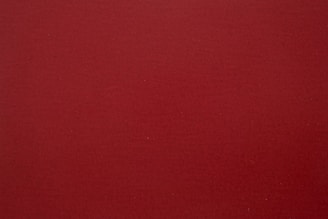 A plain, solid-colored surface in a rich dark red hue with a slightly textured appearance.