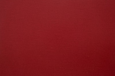 A plain, solid-colored surface in a rich dark red hue with a slightly textured appearance.