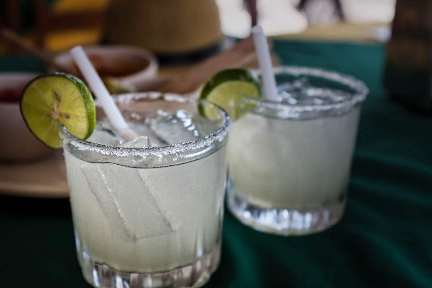 Three jumbo specialty margaritas with grilled fruit garnish on colorful Fiestaware platters